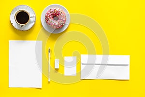 Come up with brand identity. Blank stationery for branding near coffee and donut on yellow background top view mockup