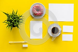 Come up with brand identity. Blank stationery for branding near coffee and donut on yellow background top view mockup