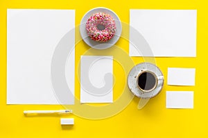 Come up with brand identity. Blank stationery for branding near coffee and donut on yellow background top view mockup