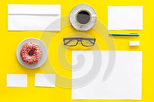 Come up with brand identity. Blank stationery for branding near coffee and donut on yellow background top view mockup