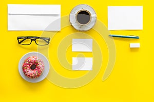 Come up with brand identity. Blank stationery for branding near coffee and donut on yellow background top view mockup