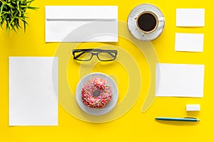 Come up with brand identity. Blank stationery for branding near coffee and donut on yellow background top view mockup