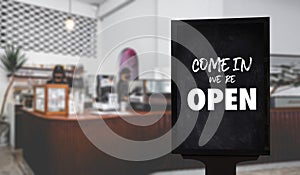 Come in Weâ€™re Openâ€™ on cafe waiter standing in front of coffee shop vintage retro sign