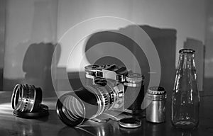 Comeback of film photography concept with vintage range finder analog camera,lens,film canister and camera film, black and white,