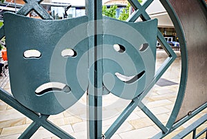 Comedy & Tragedy. Metal masks on gate in Woking town centre. Surrey, England.