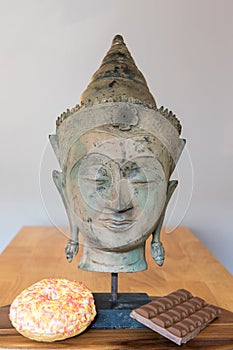 Comfort food. Self-control and temptation. Buddha with donut and chocolate