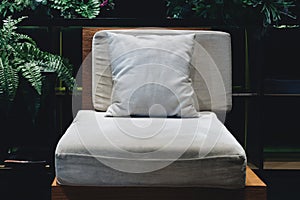 Comfort wooden chair with soft cotton pillow and cushion in low light ready to rest within decorative garden living room style.