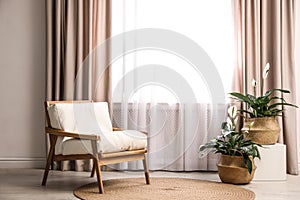 Comfortable armchair near window with elegant curtains