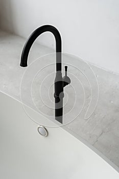 Comfortable bathtub with black modern faucet in contemporary bathroom