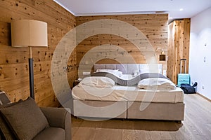 Comfortable bed in illuminated rustic style bedroom at luxurious hotel