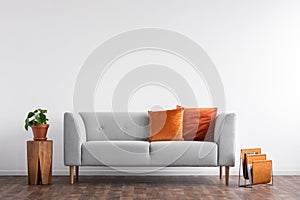 Comfortable couch with orange and red pillow in spacious living room interior,