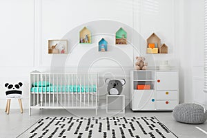 Comfortable crib near wall with color shelves in baby room. Interior design