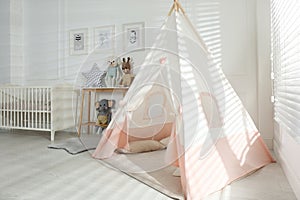 Comfortable crib and play tent in baby room. Interior design