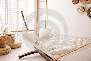 Comfortable hammock with pillows in room. Interior design