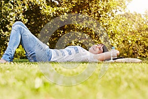 Comfortable happy woman lying in grass in autumn