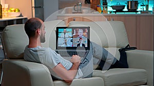 Comfortable man relaxing on couch while having online business conference