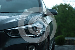 A comfortable modern powerful aggressive gray SUV stands on the street after the rain