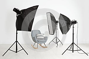 Comfortable rocking chair and professional lighting equipment in photo studio