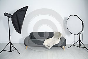 Comfortable sofa and professional lighting equipment in photo studio