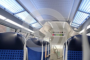 Comfortable soft blue seats with headrests in half-empty train car in Germany, concept of long-distance travel, ticket for