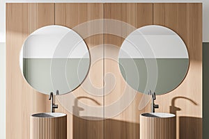 Comfortable two sinks with round mirrors standing on countertop in modern bathroom with wooden walls