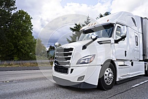 Comfortable white modern big rig semi truck running on divided h