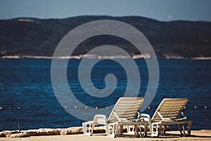 Comfortable white plastic sunbeds on beach.Lounge chairs for sunbathing