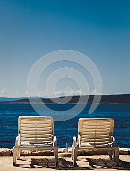 Comfortable white plastic sunbeds on beach.Lounge chairs for sunbathing