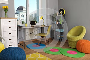 Comfortable workplace with modern laptop near window in child room. Interior design