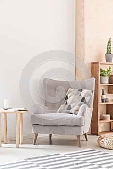 Comfy armchair with patterned pillow next to a wooden coffee tab