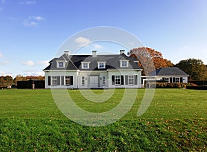 A comfy white mansion surrounded by a perfect lawn