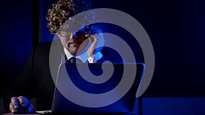 Comic adult man dressed in business suit and funny curly wig on head, calling working in office