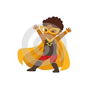Comic brave black kid in superhero colorful Halloween costume with mask and developing in the wind yellow cape, posing