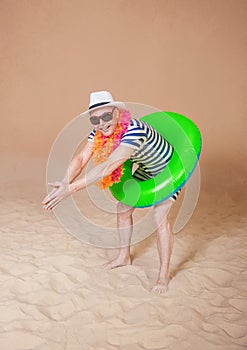 Comic funny man in vintage style striped swimsuit, colorful boa and sunglasses ready to dive with inflatable ring