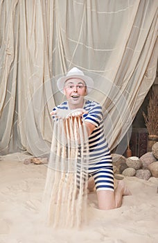 Comic funny man in vintage style striped swimsuit hold sand to sprinkle