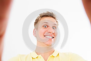 Comic mad man in casual t shirt smiling on camera with thumb up while taking selfie isolated over white background
