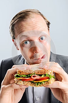 Comical man eating sandwich with funny expression