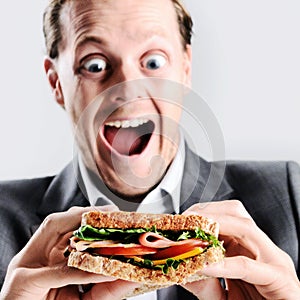 Comical man eating sandwich with funny expression