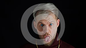Comical stupid stylish man making funny silly face grimace, playing fool, showing tongue, brainless photo