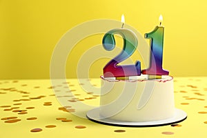 Coming of age party - 21st birthday. Delicious cake with number shaped candles on yellow background, space for text