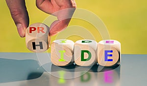 Coming out concept. Hand turns a cube and changes the word `hide` to `pride`