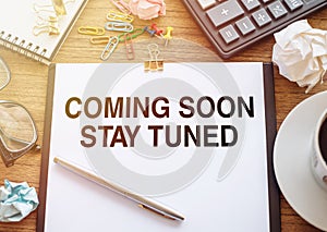 Coming Soon Stay Tuned wording on a white paper on wooden office background