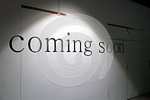 COMING SOON word on white background in the tungsten light on the wood cover fence or facade retail in under construction process