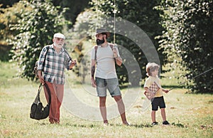 Coming together. Happy grandfather, father and grandson with fishing rods. Anglers. Men day.