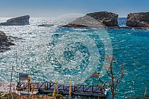 Comino blue lagoon in malta island during high wind and noon sunlight, reflection on blue water