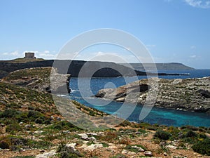 COMINO, MALTA - Apr 27, 2014: View of Santa Marija Tower, standing guard over the cliffs and blue sea of the island of Comino