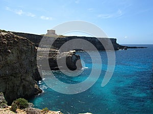 COMINO, MALTA - Apr 27, 2014: View of Santa Marija Tower, standing guard over the cliffs and blue sea of the island of Comino