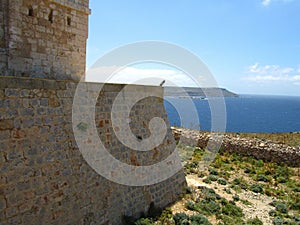 COMINO, MALTA - Apr 27, 2014: View of Santa Marija Tower, standing guard over the cliffs and blue sea of the island of Comino