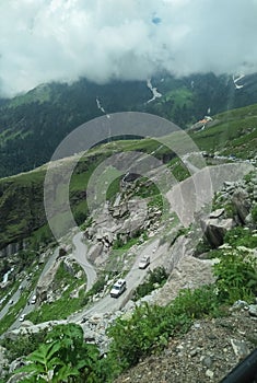 Commendable view of Himalayan curved road with big stones and mountains covered with clouds in tourism of manali, Himachal pradesh