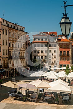 Commerce Square in Coimbra with restaurant tables and umbrellas on a sunny day lunch time - Portugal, Coimbra, Vetical